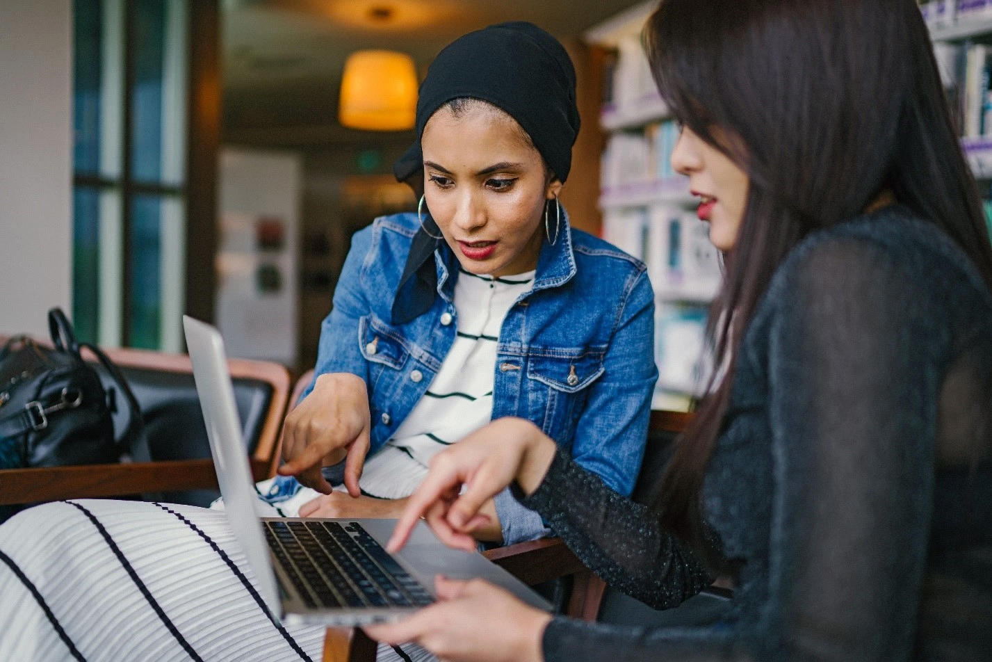 Two people researching fixed vs variable expenses on computer.