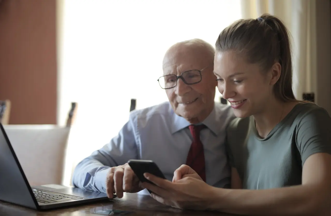 Old man and young lady looking at line of credit on phone.