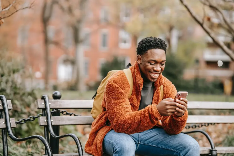 Person sitting on bench researching benefits of an online line of credit on their phone.