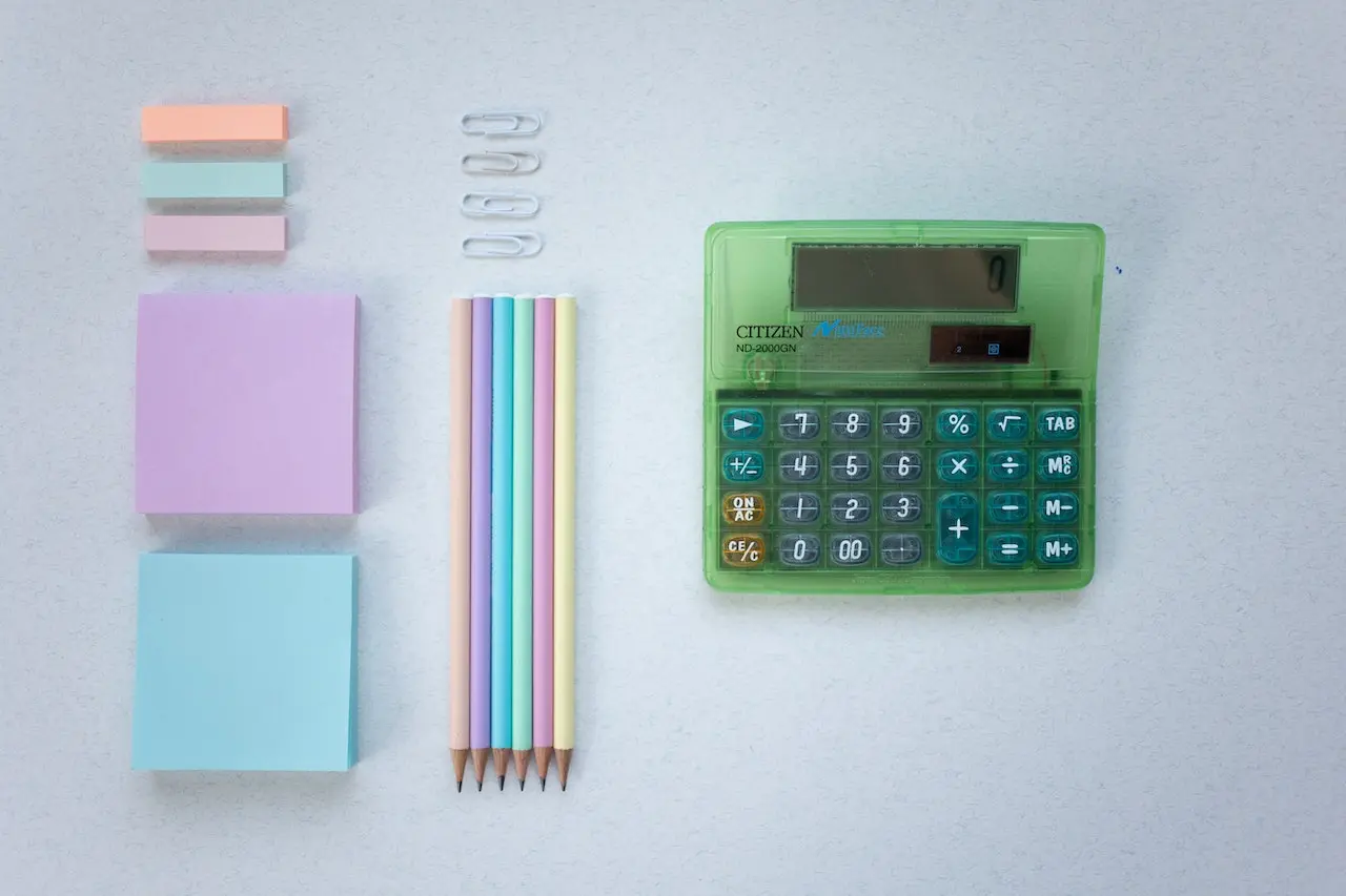Stationary and calculator on grey table.